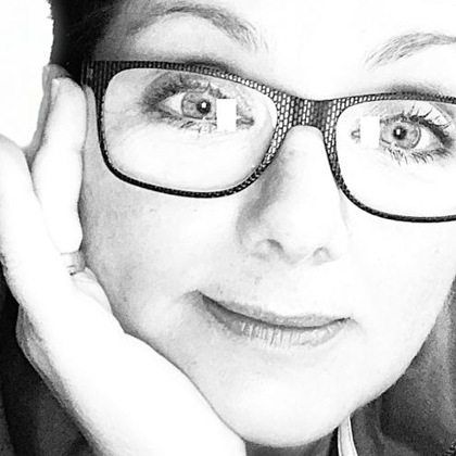 Schwarz-Weiß-Motiv von Martina Weber-Grundmann: Angeschnittenes Gesicht mit gemusterter Brille und Hand an der Wange blickt freundlich, mit strahlenden Augen